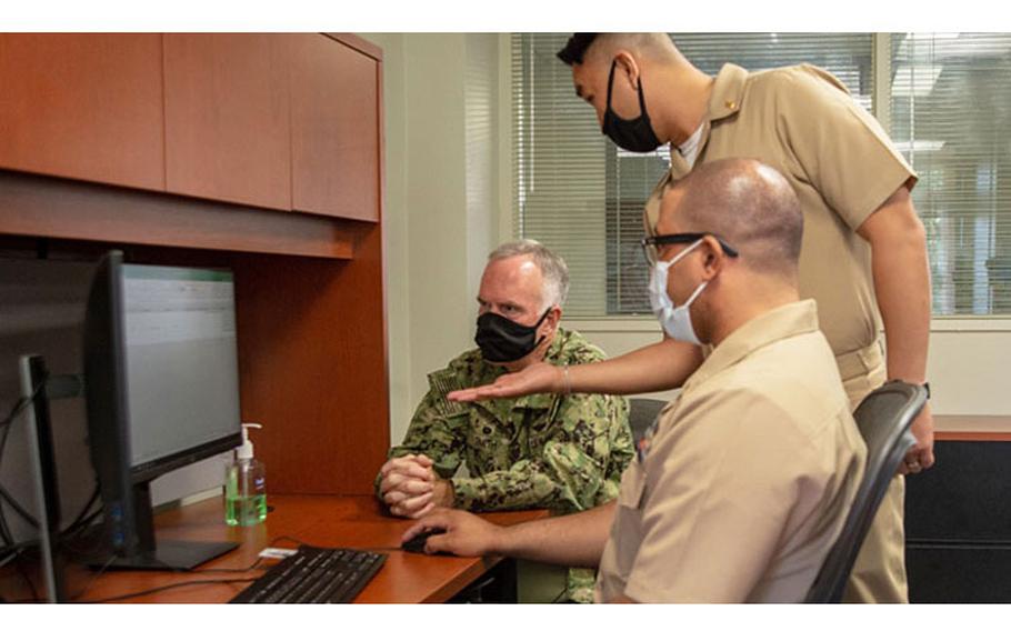 Navy Capt. Bradford Smith (left), commanding officer of Naval Medical Center San Diego, enrolls in MHS GENESIS with the help of training coordinators Navy Lt. Donny Le (standing) and Navy Petty Officer 2nd Class Terrance Stevens. (Photo by Petty Officer 3rd Class Jake Greenberg)