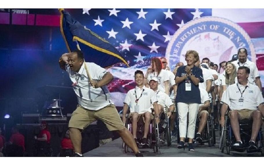 Amy Cozad (center), Rear Adm. Kyle Cozad (far right) and the Navy team enter the Amalie Arena in Tampa, Florida to participate in the Department of Defense Warrior Games this past June. More than 300 athletes from the U.S. and six partner nations competed in the 2019 DoD Warrior Games. (Photo by Roger Wollenberg.)