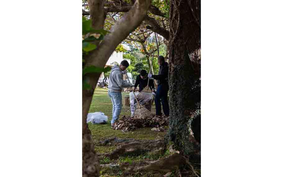 U.S. Marine Corps Lance Cpl. Ronaldo Gomez, left, Lance Cpl. Anthony Williams, right, and U.S. Navy Religious Program Specialist Seaman Apprentice Sean Frantzis rake fallen leaves during a volunteer event at Hikarigaoka Nursing Home, Okinawa, Japan.