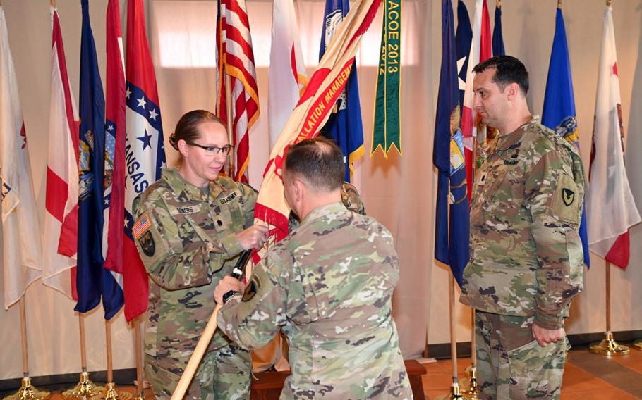 Col. Christopher L. Tomlinson, center, commander of U.S. Army Garrison Japan, hands the USAG Okinawa unit colors to incoming Commander Lt. Col. Rachel R. Bowers, left, as outgoing Commander Lt. Col. Ryan S. Gladding looks on during a change-of-command ceremony held June 30 at Torii Station, Okinawa. (Ichiro Tokashiki)