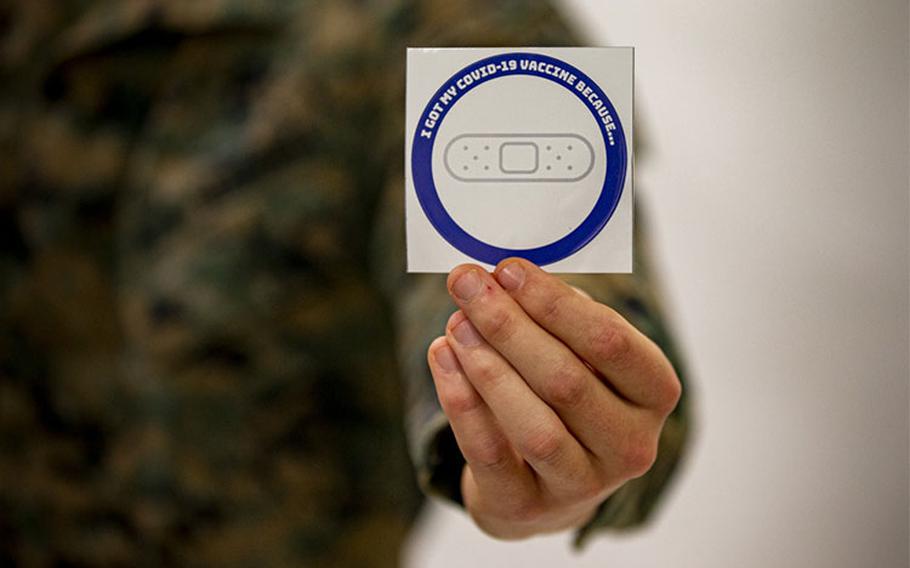 A U.S. Marine holds out a sticker given to Marines after receiving the COVID-19 vaccination at the U.S. Naval Hospital Okinawa, on Camp Foster, Feb. 18, 2020. As thousands of service members are receiving the COVID-19 vaccination, they are given a sticker stating ‘I got my COVID-19 vaccine because…’ This personal memento signifies their own unique reason to receive the vaccine. (Courtesy photo by Staff Sgt. Lucas Vega)