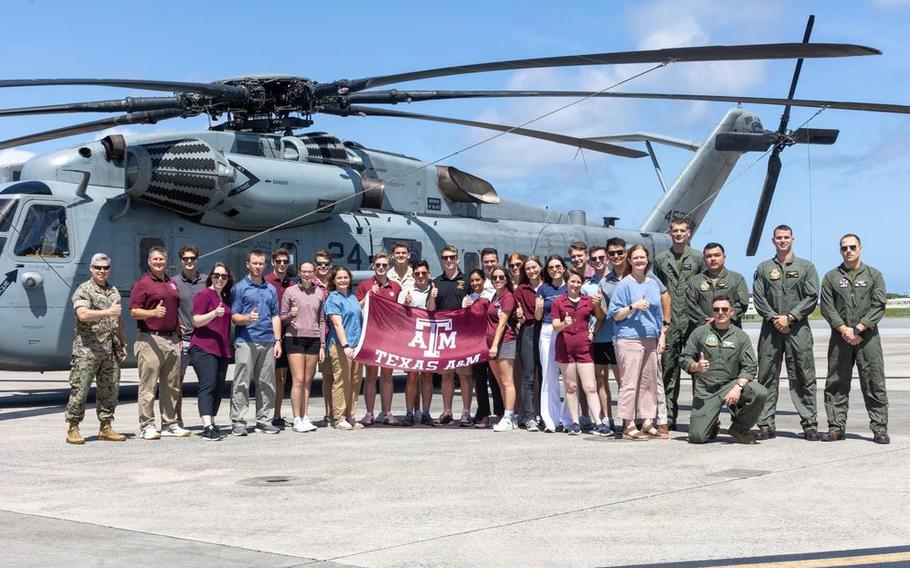 U.S. Marines with 1st Marine Aircraft Wing and Texas A&M University Reserve Officer Training Corps students pose in front of a CH-53E Super Stallion helicopter on Marine Corps Air Station Futenma, Okinawa.