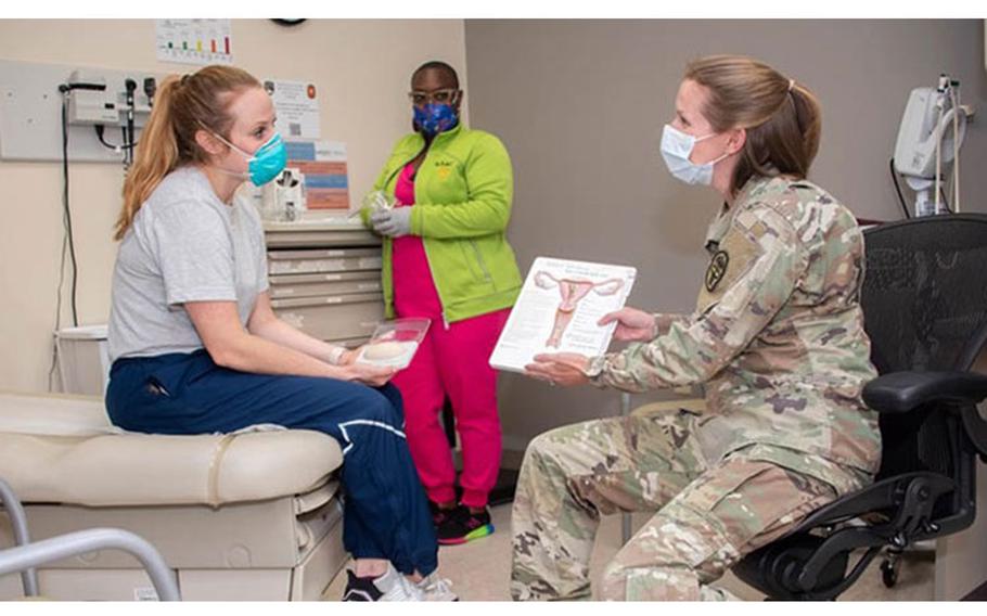 Army Maj. (Dr.) Kayla Jaeger, Adolescent and Young Adult Medicine chief, discusses contraception options with patient, Air Force Capt. Jacqueline Wade, while Benesha Jackson, licensed vocational nurse, gathers instruments for an exam at the CPT Jennifer M. Moreno Primary Care Clinic, Fort Sam Houston, Texas. (U.S. Army photo by Jason W. Edwards)