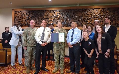 Photo Of Kadena Officers’ Club staff group photo as Stars and Stripes Pacific Commander Lt. Col. Marci Hoffman presents award.