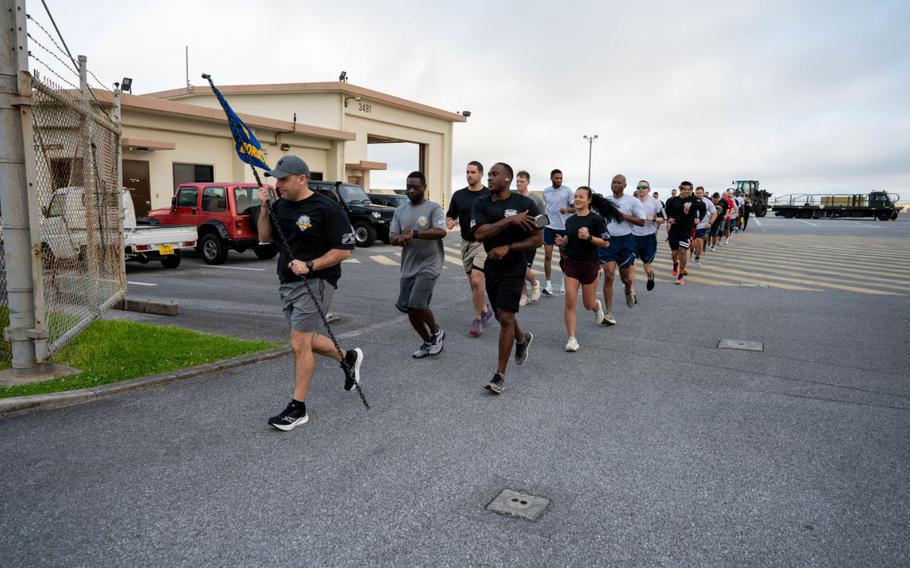 U.S. Air Force Airmen participate in the Port Dawg Memorial Run at Kadena Air Base, Japan, May 16, 2025. The PDMR flag adorns a heavy chain staff, which represents the responsibility passed down to Airmen in the career field from Port Dawgs that have lost their lives in the line of duty. 