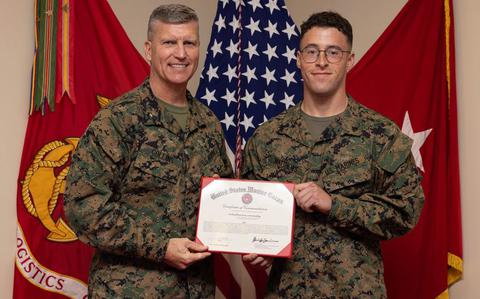 Photo Of Brigadier General Kevin G. Collins and Cpl. Logan Matthews pose with the award on their hands.