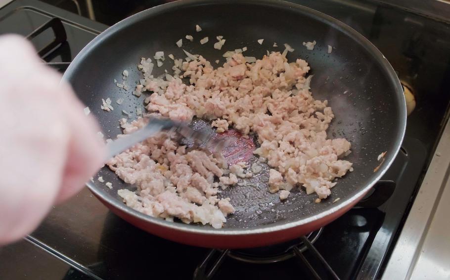 Fry chopped onion with olive oil in a pan. Once the onion becomes soft, add garlic, ground beef, and pork before further frying the mixture.