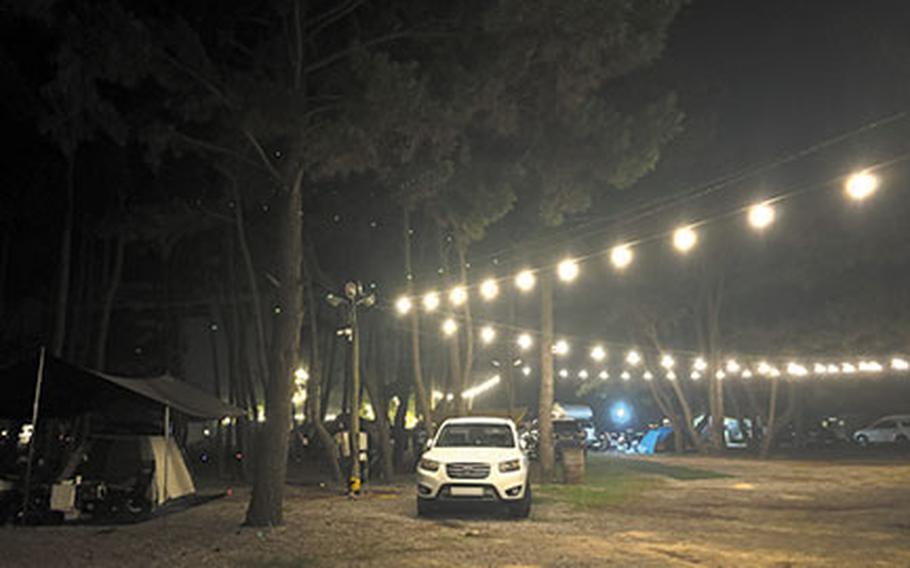 Camping site at night. A car is parked beside a tent.