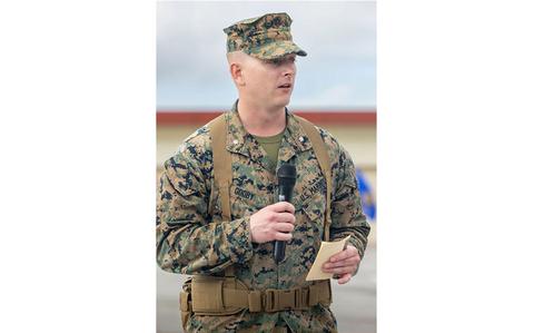 Photo Of Lt. Col. Jacob Godby gives remarks. a microphone and a note is on his hands.