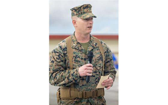 Lt. Col. Jacob Godby gives remarks. a microphone and a note is on his hands.