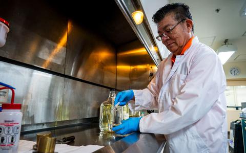 Photo Of Atsushi Matsuda extracts JP-8 fuel under a fume hood during testing.