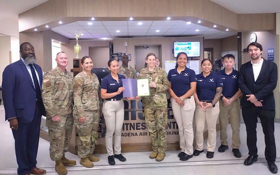 Photo Of Risner Fitness Center staff group photo as Stars and Stripes Pacific Commander Lt. Col. Marci Hoffman presents award.