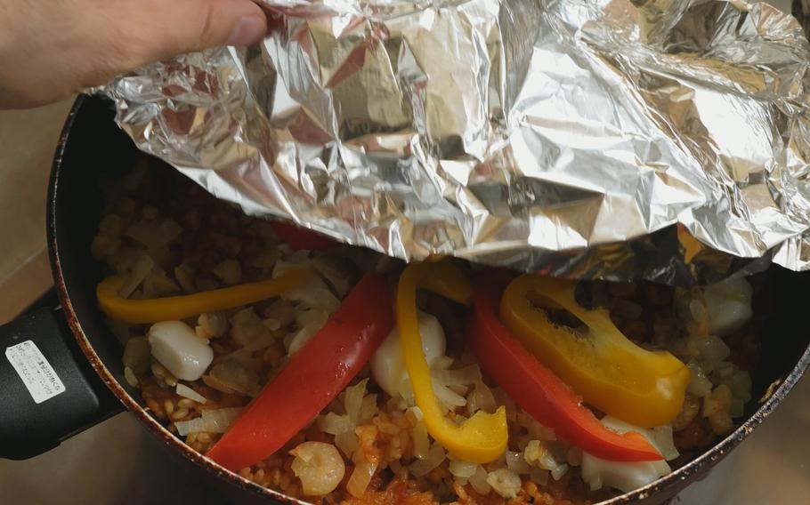 Take the cover off and put the seafood and sliced bell peppers on top of the rice. Cover the frying pan with the aluminum foil again and cook it over low heat for another 10 minutes.