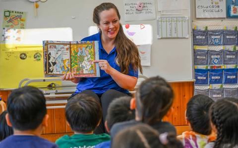 Photo Of Candice Barber, Public Affairs Officer for Commander, Fleet Activities Okinawa (CFAO), reads to children during a CFAO-led community relations event at a school in Kadena Town, Okinawa, Japan, June 16, 2025.