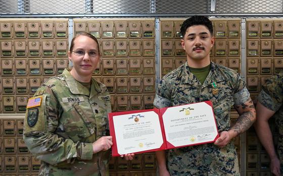 U.S. Marine Cpl. David Guzman, a postal clerk with Marine Corps Installation Pacific, receives The Navy and Marine Corps Achievement Medal from Lt. Col. Rachel Bowers, U.S. Army Garrison Okinawa commander, at the Torii Station Post Office, Okinawa, Japan, on April 28, 2025. Guzman was temporarily assigned to USAG Okinawa to train new personnel at the Army Post Office. 