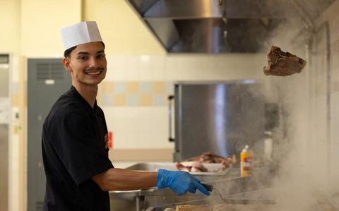 Photo Of U.S. Marine Corps Anthany Castillo poses while cooking in the kitchen.