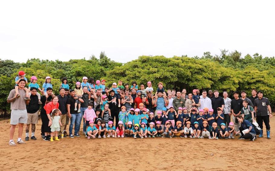 U.S. service members with Camp Hansen Single Marine Program and local preschool students and staff members pose for a group photo after an Earth Day cleanup and mangrove-planting event at Nature Mirai Kan in Kin Town, Okinawa, Japan, April 25, 2025.