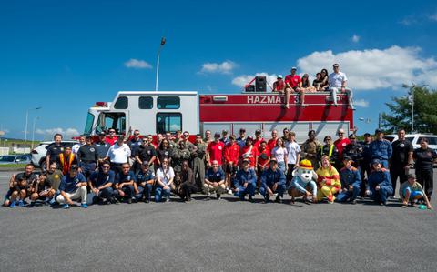 Photo Of Firefighters stationed in Okinawa and 18th Wing leadership pose for a group photo in front of a fire truck.