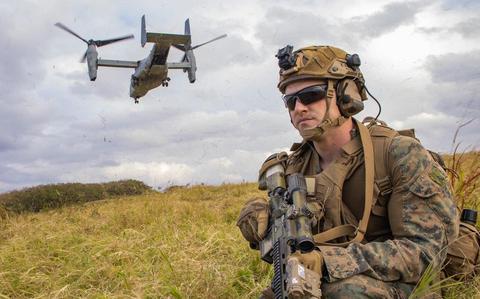 Photo Of Lance Cpl. Justin Watkins posts security during a tactical recovery of aircraft and personnel exercise. A combat plane is flying close to him.