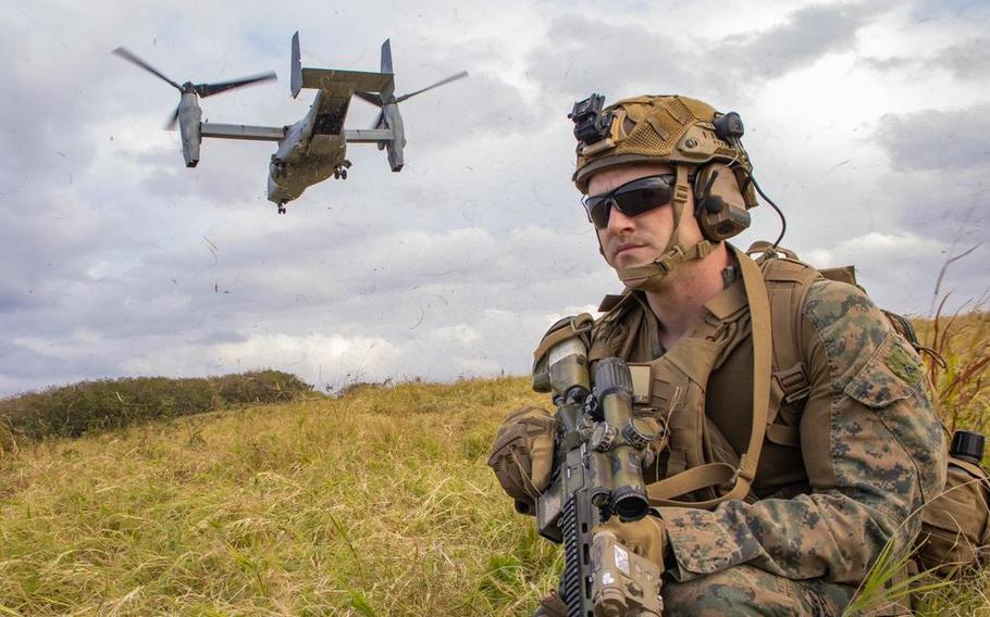 Lance Cpl. Justin Watkins posts security during a tactical recovery of aircraft and personnel exercise. A combat plane is flying close to him.