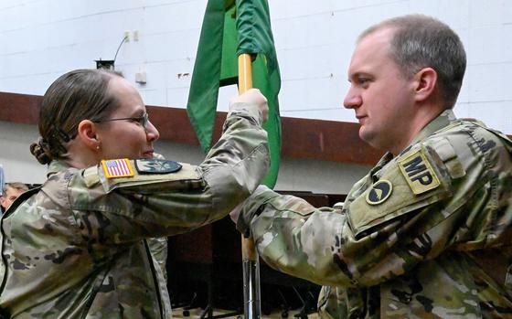 U.S. Army Garrison Okinawa Lt. Col. Rachel Bowers, commander, passes the detachment guidon to Capt. Lawrence Jerichow, incoming 247th Military Police Detachment commander, during a change of command ceremony at Torii Station, Japan, May 13, 2025. Soldiers and leaders gathered to witness the symbolic transfer of authority.