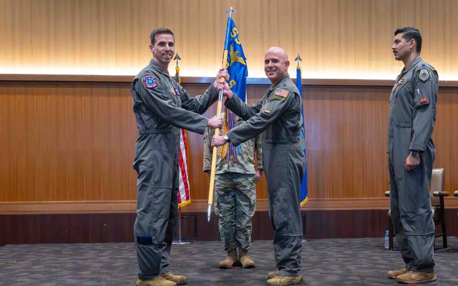 U.S. Air Force Col. John Isacco, left, 55th Operations Group commander, takes the guidon from Lt. Col. John Casey, right, outgoing 82nd Reconnaissance Squadron commander at Kadena Air Base, Japan, June 3, 2025. Passing the unit’s guidon is a tradition where the outgoing commander symbolically relinquishes responsibility and authority to the incoming commander.