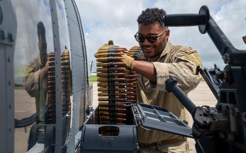 Photo Of U.S. Air Force Staff Sgt. Jordan Florio, 33rd Rescue Squadron special missions aviator, loads ammunition to a GAU-21 machine gun on a HH-60W Jolly Green II assigned to the 33rd RQS before a gunnery training sortie at Kadena Air Base, Japan.