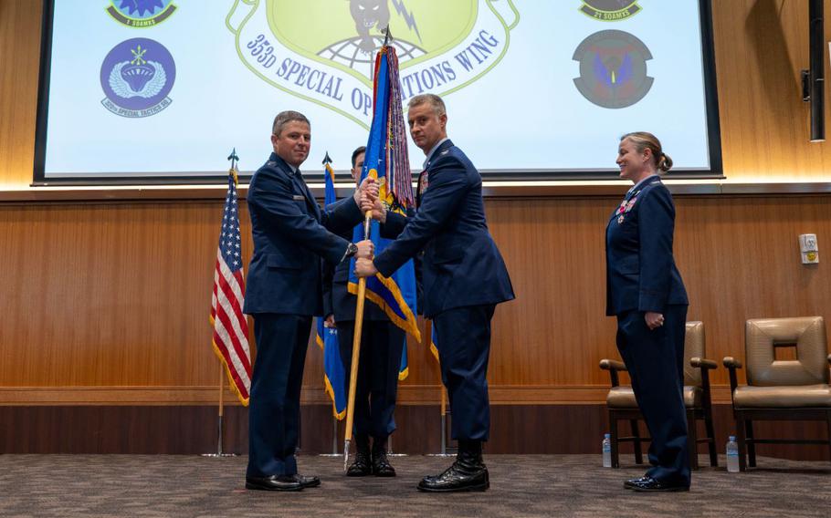 U.S. Air Force Lt. Gen. Michael Conley, commander Air Force Special Operations Command, passes the organizational flag of the 353rd Special Operations Wing to Col. Stewart Parker, incoming 353rd SOW commander, during a change of command ceremony at Kadena Air Base.