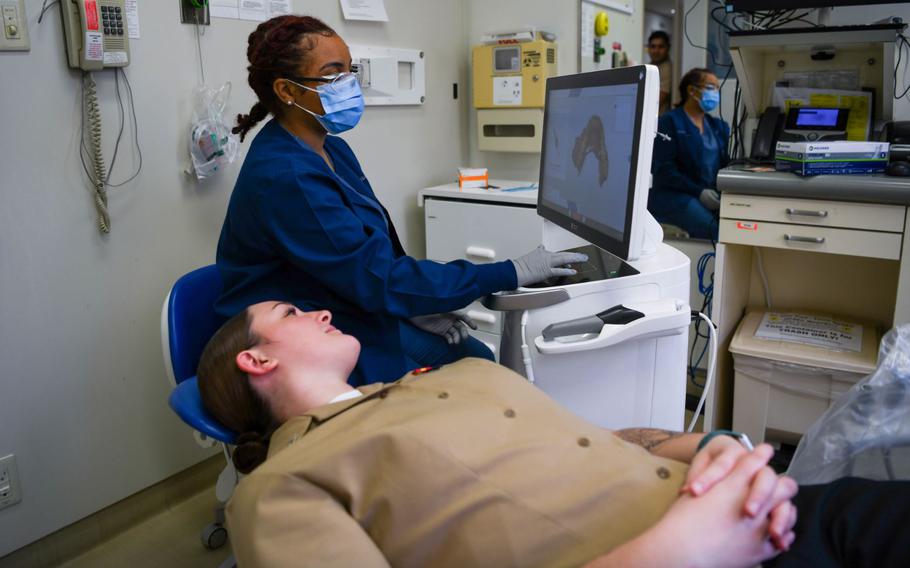 U.S. Air Force Airman 1st Class Aliyah Parker, back, 18th Dental Squadron orthodontic technician, utilizes a Computer Aided Design and Computer Aided Manufacturing machine on U.S. Navy Hospital Corpsman 3rd Class Mackenzi Barksdale, front, 3rd Dental Battalion dental technician, to make a 3D model of their own mouth during the 67th Tri-Service Dental Conference at Kadena Air Base, Japan, March 13, 2024.