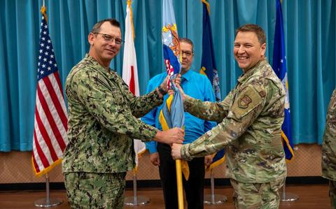 Photo Of U.S. Navy Capt. Patrick Brown, Defense Logistics Agency Indo-Pacific commander, left, passes the guidon to U.S. Air Force Maj. Dominic Baker, DLA Energy Okinawa incoming commander, right, during a change of command ceremony.