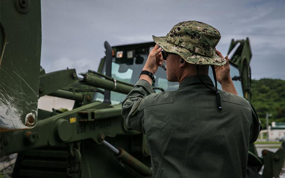 U.S. Navy BM2 Truong Le, boatswain's mate with Naval Beach Unit (NBU) 7, ground guides a bulldozer aboard a Landing Craft Air Cushionn (LCAC) on Naval Base White Beach, Okinawa, Japan, June 1, 2021.