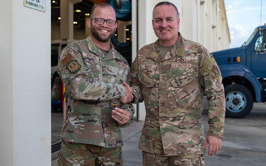 Chief Master Sgt. David Wolfe, right, Pacific Air Forces command chief, and Tech. Sgt. Geoffrey Rowland, 718th Civil Engineering unaccompanied housing non-commissioned officer in charge, pose with a coin at Kadena Air Base, Japan, June 9, 2023. During his visit, Wolfe toured different facilities, recognized Airmen for excellent performance and held open question discussions with units to better understand Kadena operations. (U.S. Air Force photo by Airman 1st Class Jonathan R. Sifuentes)