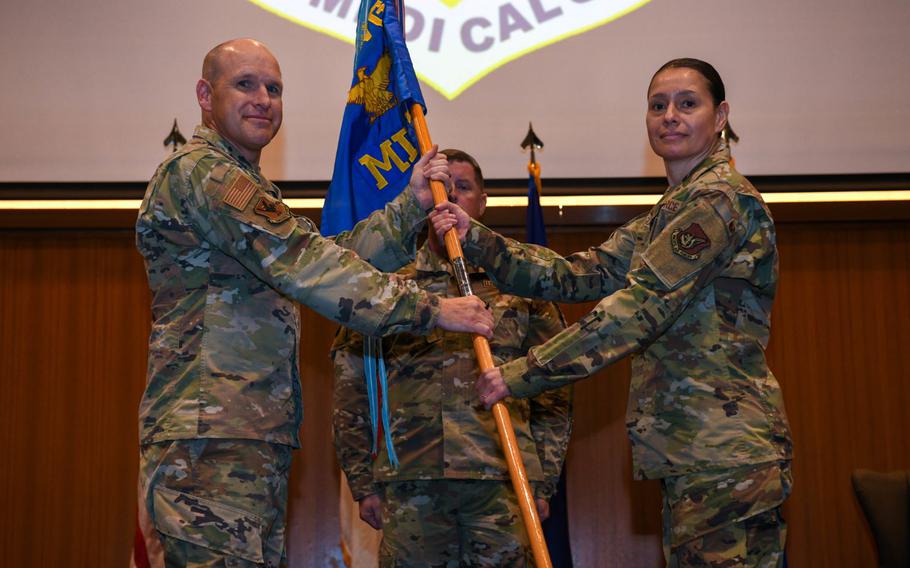 U.S. Air Force Brig. Gen. Nicholas Evans, left, 18th Wing commander, passes the guidon to U.S. Air Force Col. Lisa Guzman, right, incoming 18th Medical Group commander, during the change of command ceremony at Kadena Air Base, Japan, June 28, 2024.