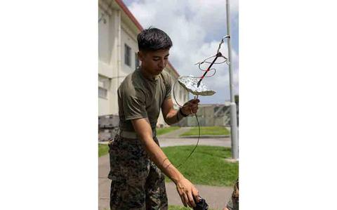 Photo Of U.S. Marine Corps Pfc. Bryan Chijate, a transmissions system operator with 5th Air Naval Gunfire Liaison Company, III Marine Expeditionary Force Information Group, tests a field expedient radio antenna on Camp Hansen, Japan.