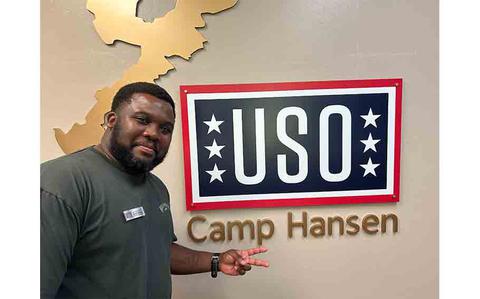 Photo Of Darryl Cockrum posing in front of USO Camp Hansen sign.