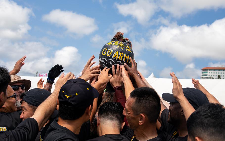 The US Army Black Knights gather around to touch a buoy with “Go Army, Beat Navy” written on it.