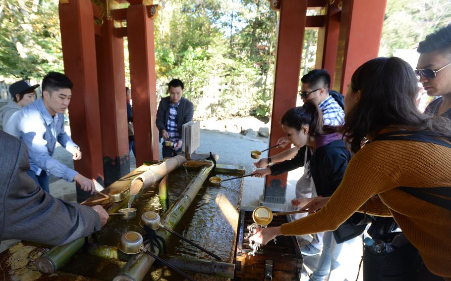 people rinsing hands at purification fountain